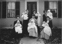 Six women holding six babies in front of a house in Vermont