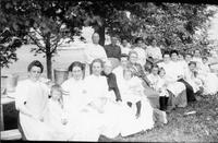 Women and young girls sitting at picnic tables.